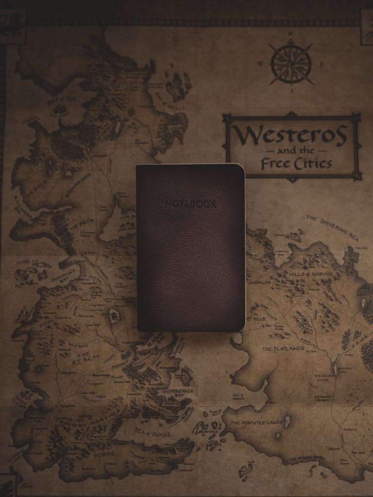 A leather notebook placed on a stylized map of Westeros from a fictional fantasy world.